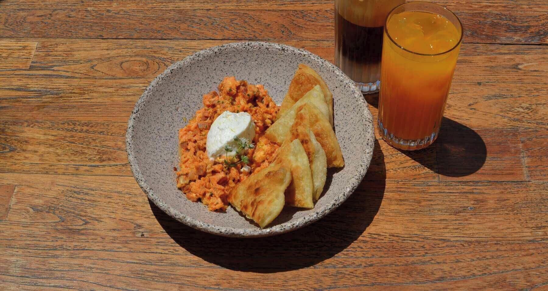 Un plato de comida con una bebida sobre una mesa de madera.