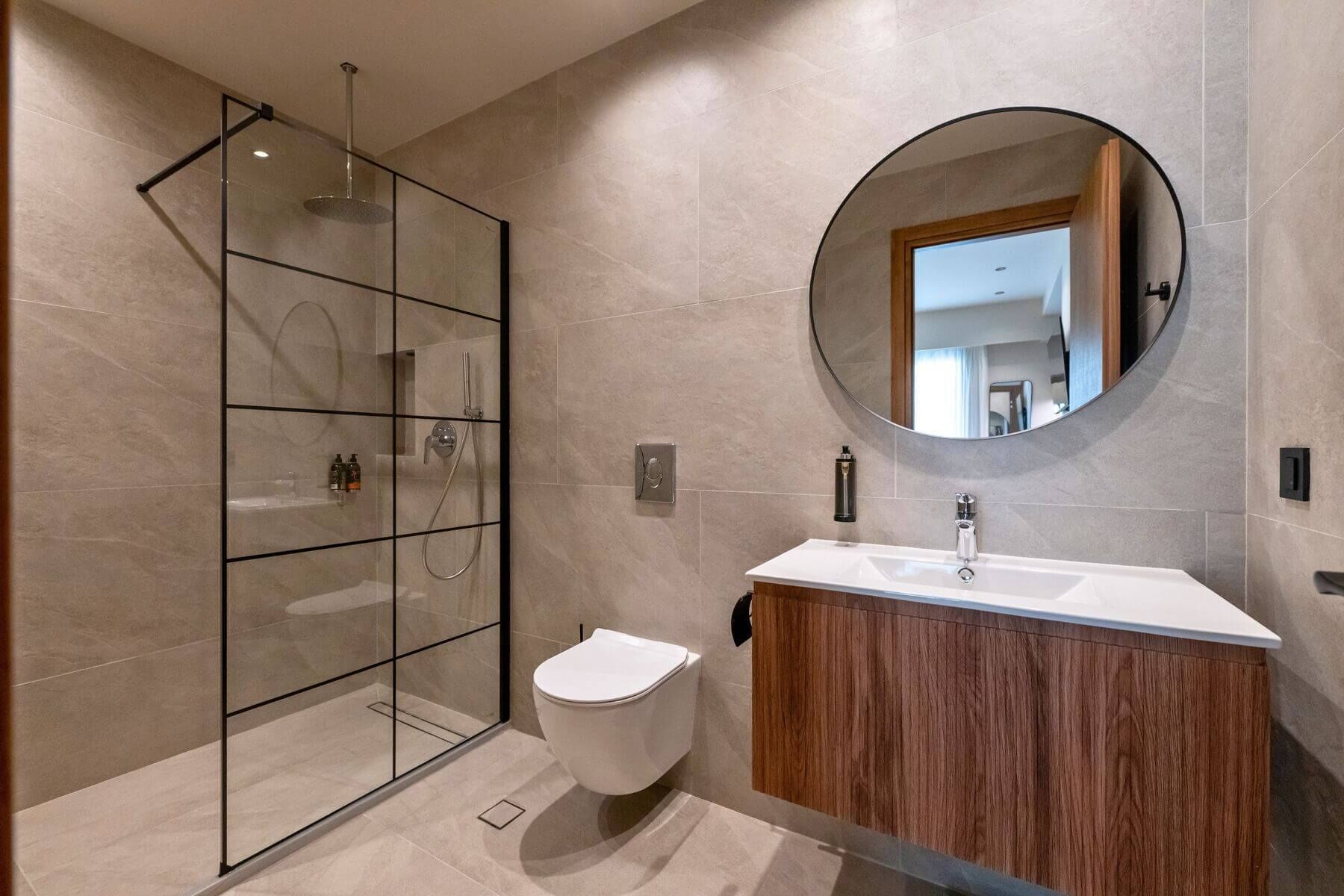 Ein modernes Badezimmer mit Duschkabine aus Glas, Toilette, Waschtisch mit Spiegel und Waschbecken.