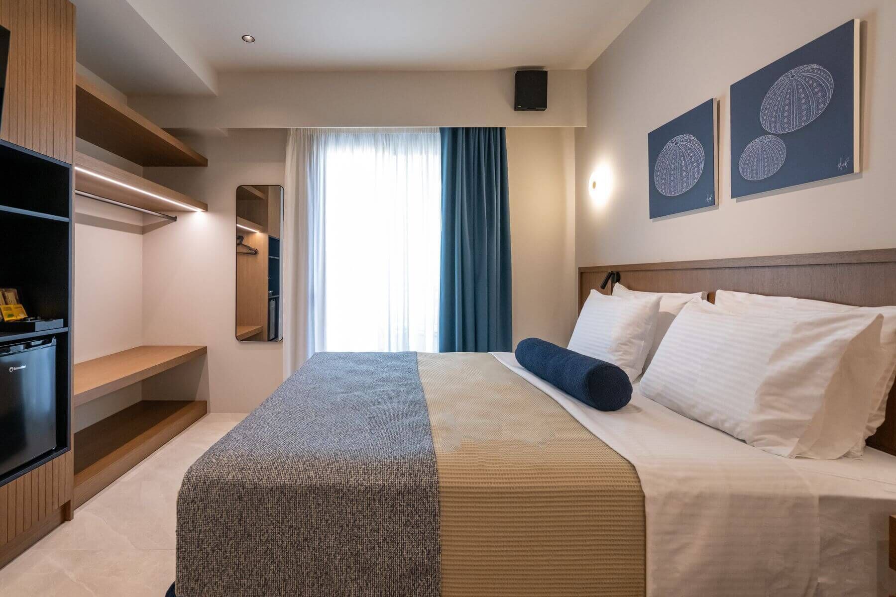 Habitación de hotel con cama, televisor, armario y obras de arte en la pared.
