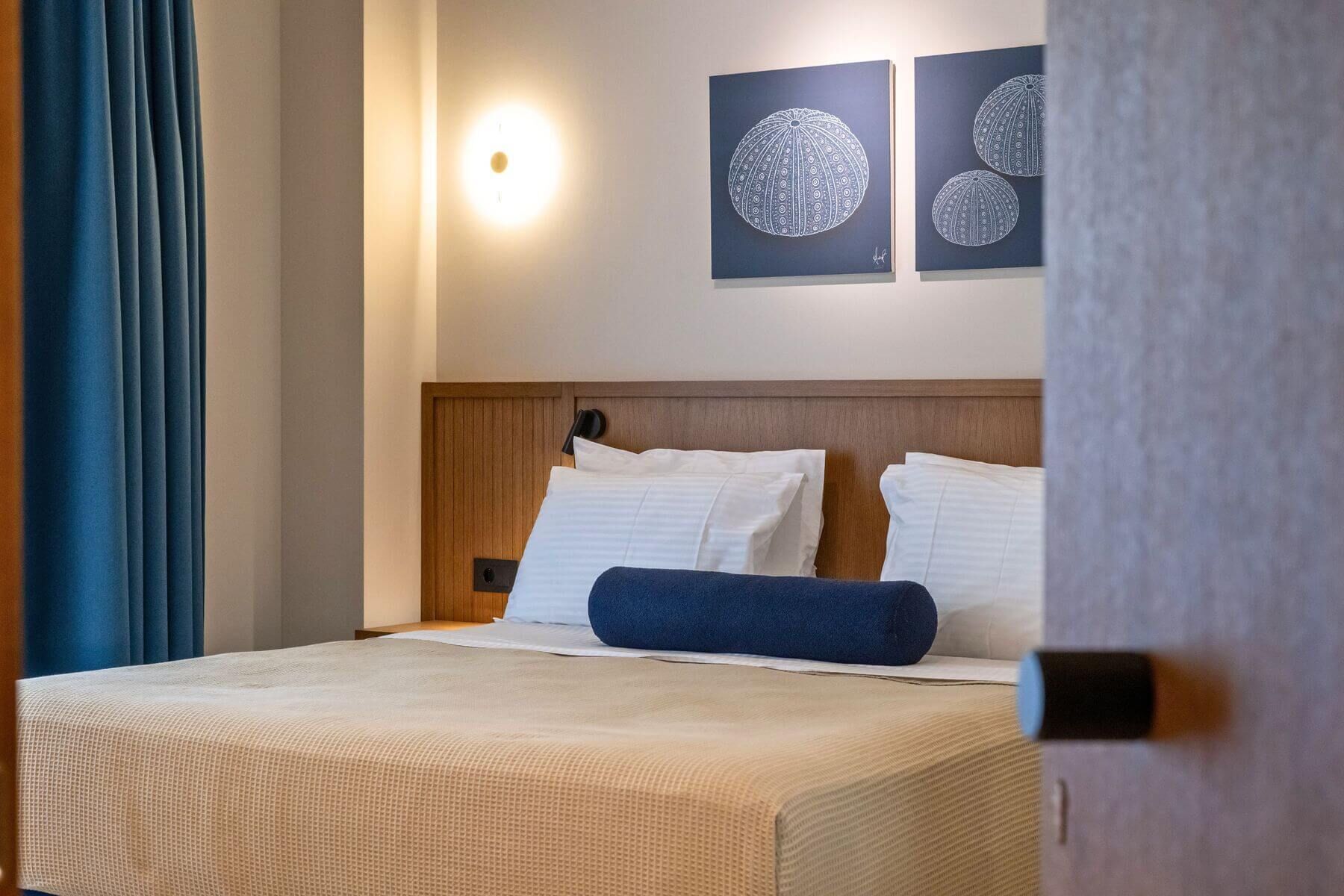 A hotel room with a bed, two pillows, a headboard, and wall art.