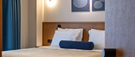 A hotel room with a bed, two pillows, a headboard, and wall art.