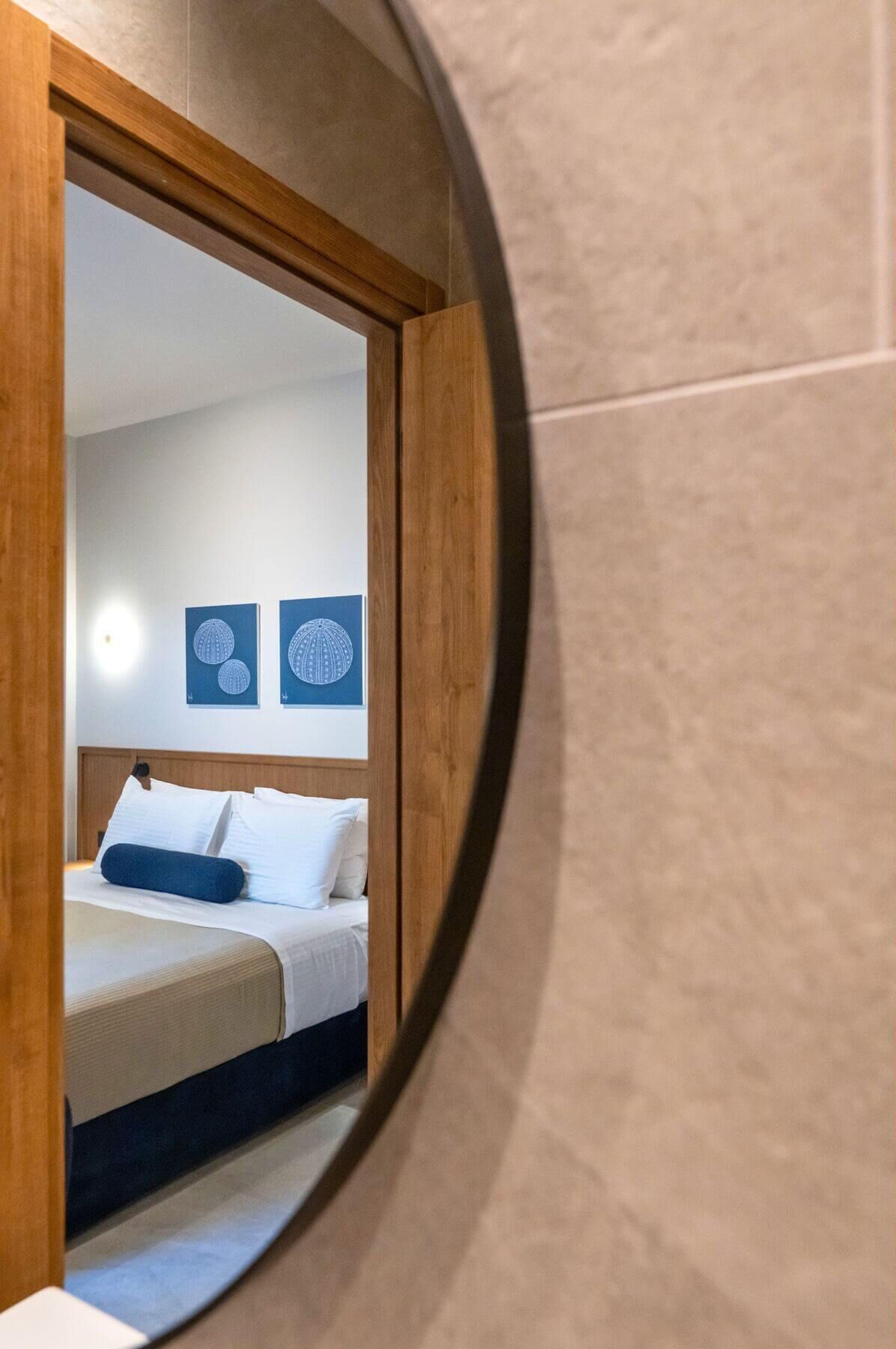 Een slaapkamer met een bed, kussens en een hoofdeinde. Boven het bed hangen twee decoratieve wanddecoraties.