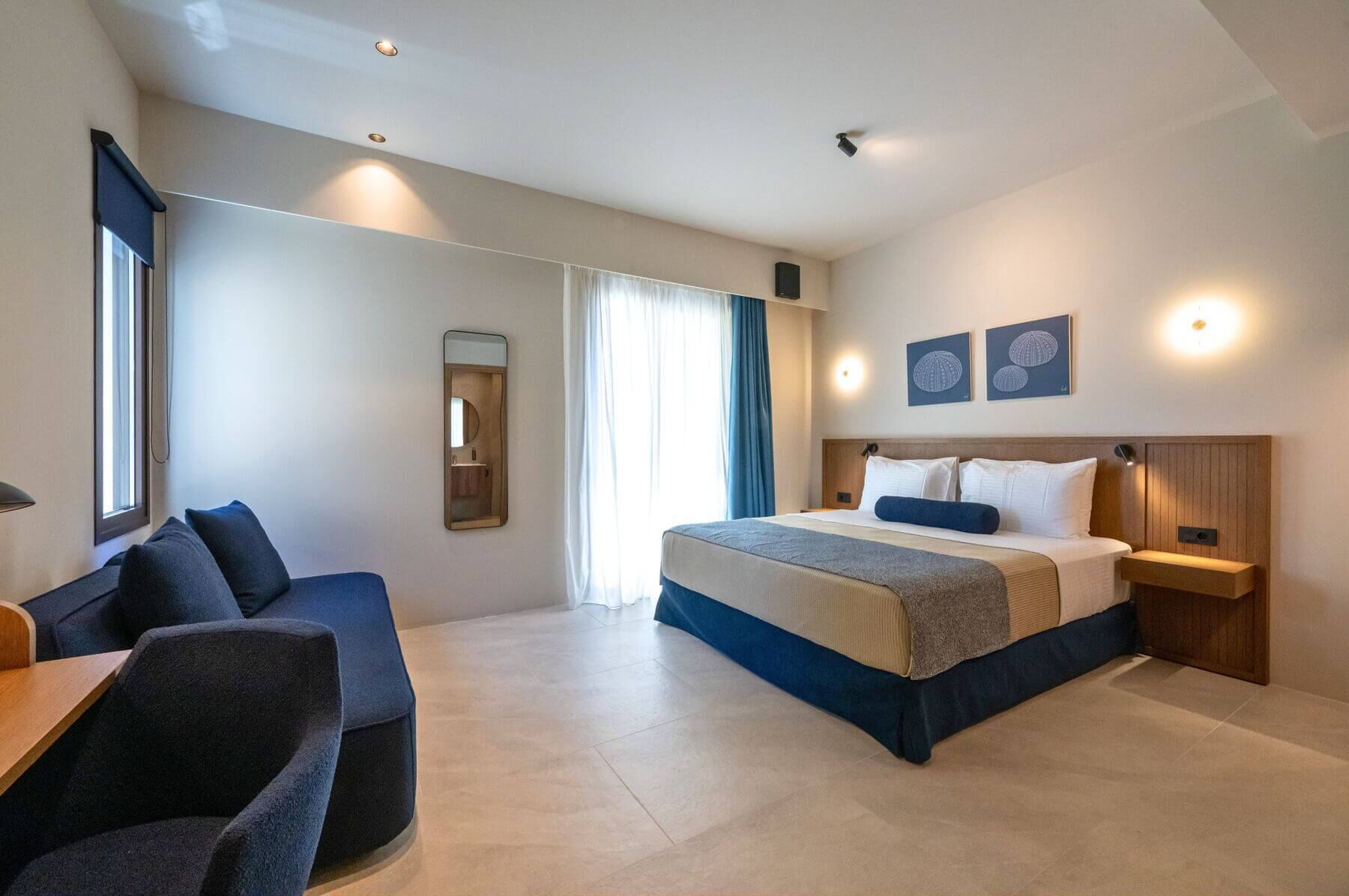 A modern hotel room with a large bed, a desk, and a seating area.