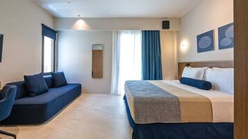 Una habitación de hotel moderna con cama, sofá, espejo y televisor de pared.