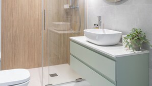 A modern bathroom with a glass-enclosed shower, a round mirror, and a white sink. - RentPlanet - Apartament Stawowa (Wroclaw)