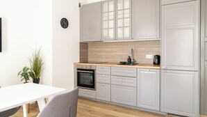 A modern kitchen with grey cabinets, a wooden countertop, and a built-in oven. - RentPlanet - Apartament Stawowa (Wroclaw)