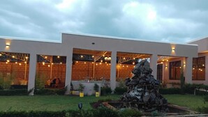 A modern building with a covered outdoor seating area, a stone pathway, and a rock feature. - Olive Hotel Narok (Narok)