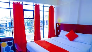 A hotel room with a large bed, red curtains, and a view of the outdoors. - Olive Hotel Narok (Narok)