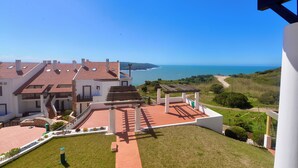 A modern house with a patio, a view of the sea, and a clear sky. - Collasão - Stunning Duplex with Pool & Sea Views (São Martinho do Porto)