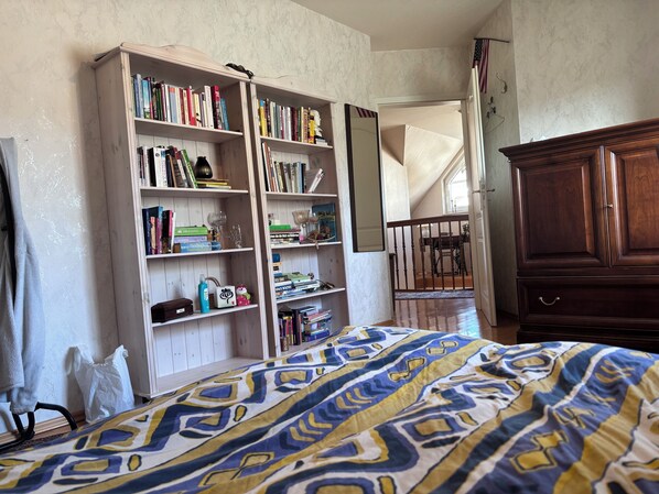 A bedroom with a large bed, a wooden bookshelf, and a wooden dresser.