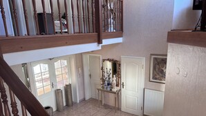 A spacious foyer with a high ceiling, a grand staircase, and a decorative console table.