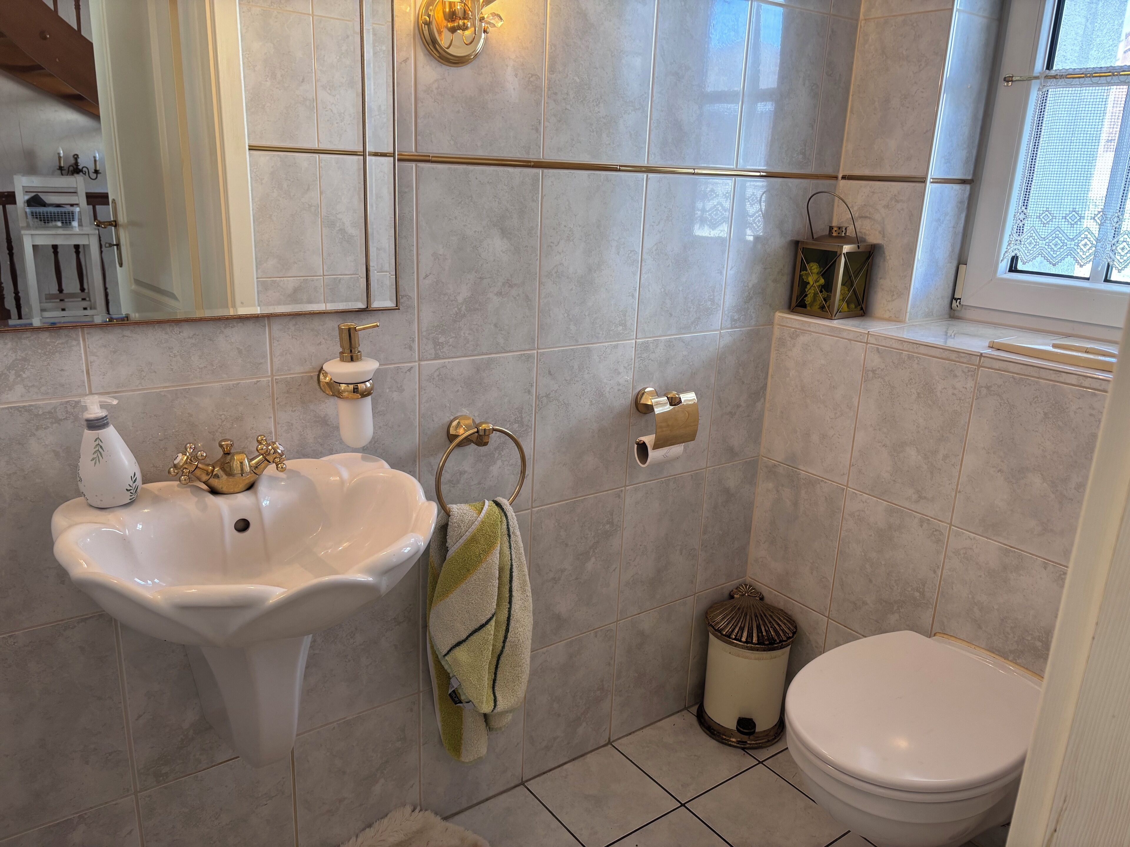 Een badkamer met een wastafel op een voetstuk, een handdoekrek, een toilet en een prullenbak.