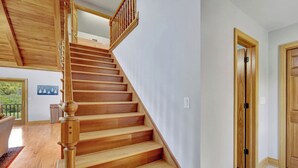 A wooden staircase leading to an upper floor, a door with a wooden frame, and a view of a room with a window and a door.