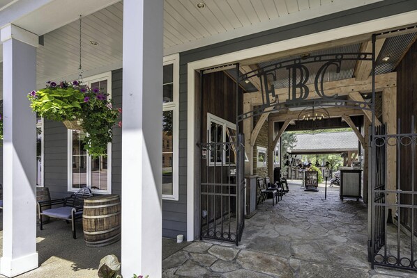 A covered outdoor seating area with a bench and a hanging flower basket.