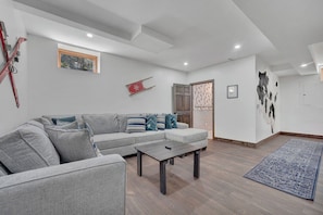 Un salon moderne avec un canapé gris, une table basse et un tapis bleu.