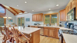 A spacious kitchen with wooden cabinets, a large island, and a view of the outdoors.
