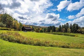 A rural landscape with a barn, open fields, and a pond.
