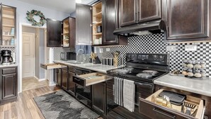 A modern kitchen with dark wood cabinets, a black stove, and a checkered backsplash.