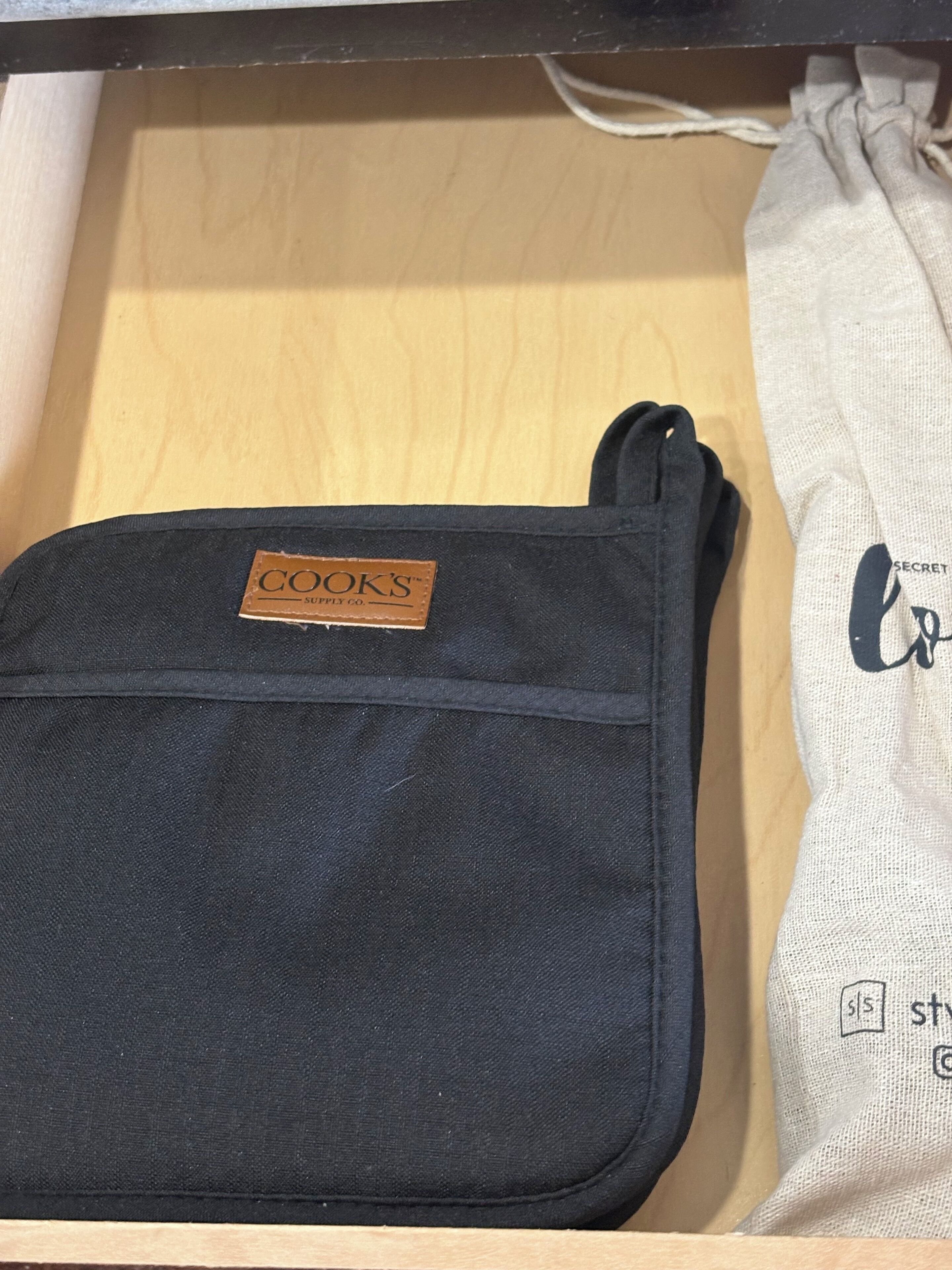 Un sac noir avec une étiquette en cuir, dans un tiroir en bois.