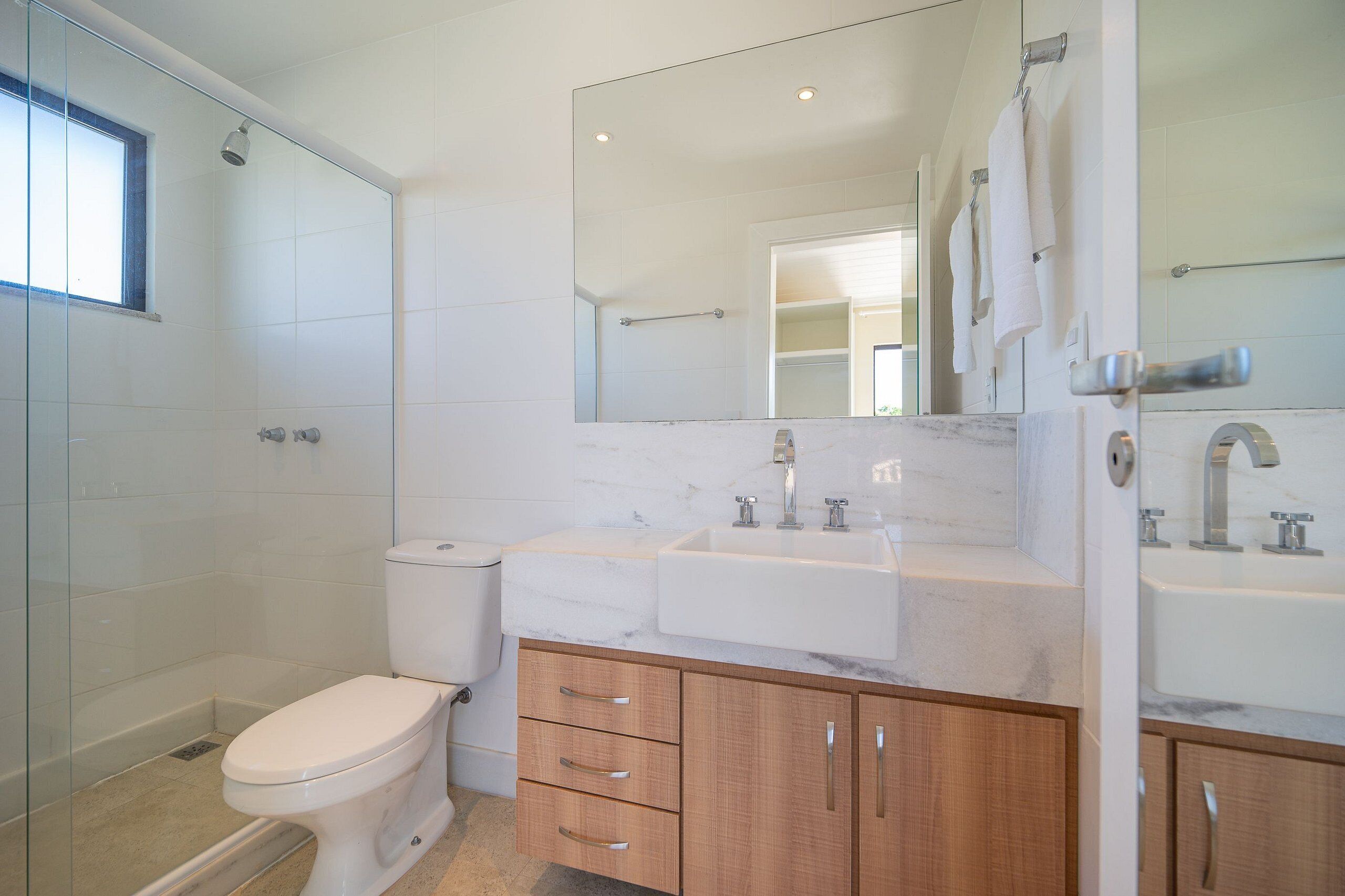 Een moderne badkamer met toilet, douche en een wastafel met twee kommen.