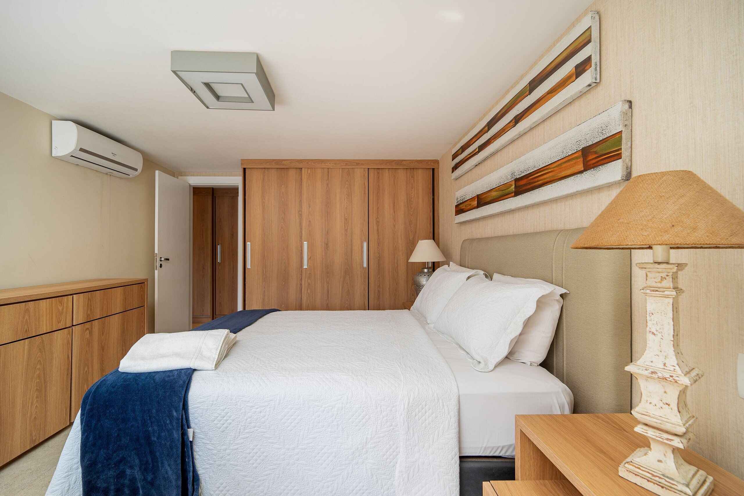 Un dormitorio con cama, armario de madera y lámpara de pared.