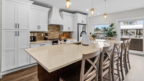 A modern kitchen with white cabinets, a large island, and pendant lighting. - 218 Oasis On Ohio: Stunning Pool Home W/ Dock Access! 3 Bedroom Home (Fort Myers Beach)