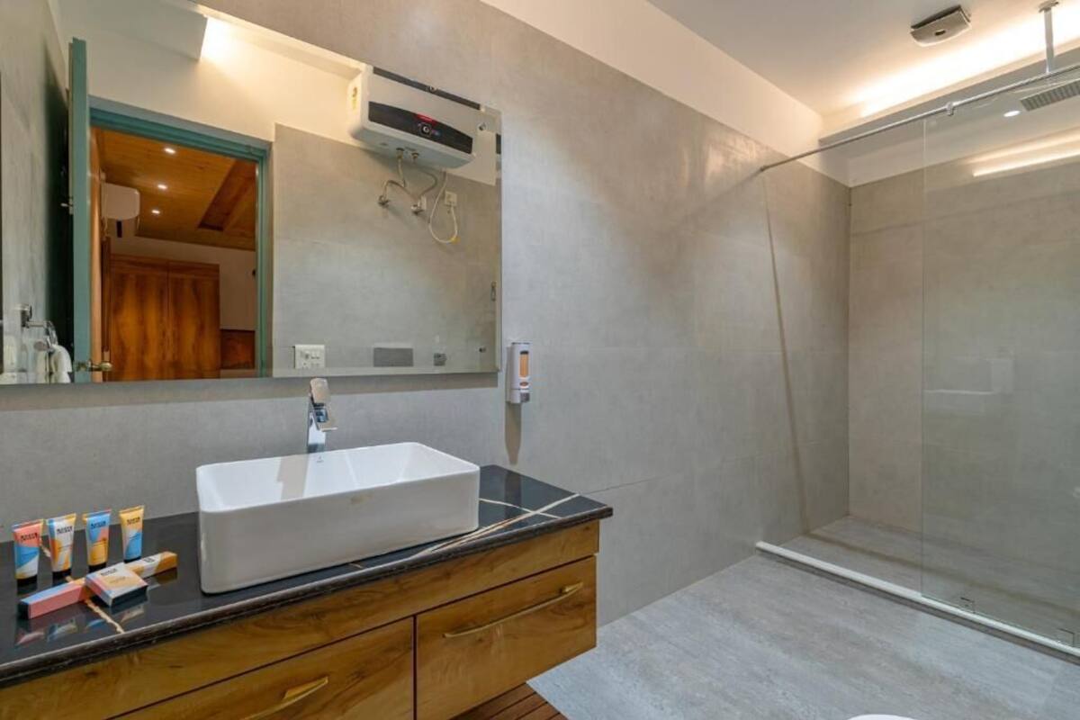 A modern bathroom with a large mirror, a white sink, and a shower enclosure.