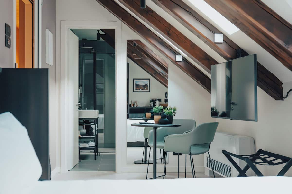 Un interior moderno con comedor, cocina y un espacio loft con vigas de madera a la vista.