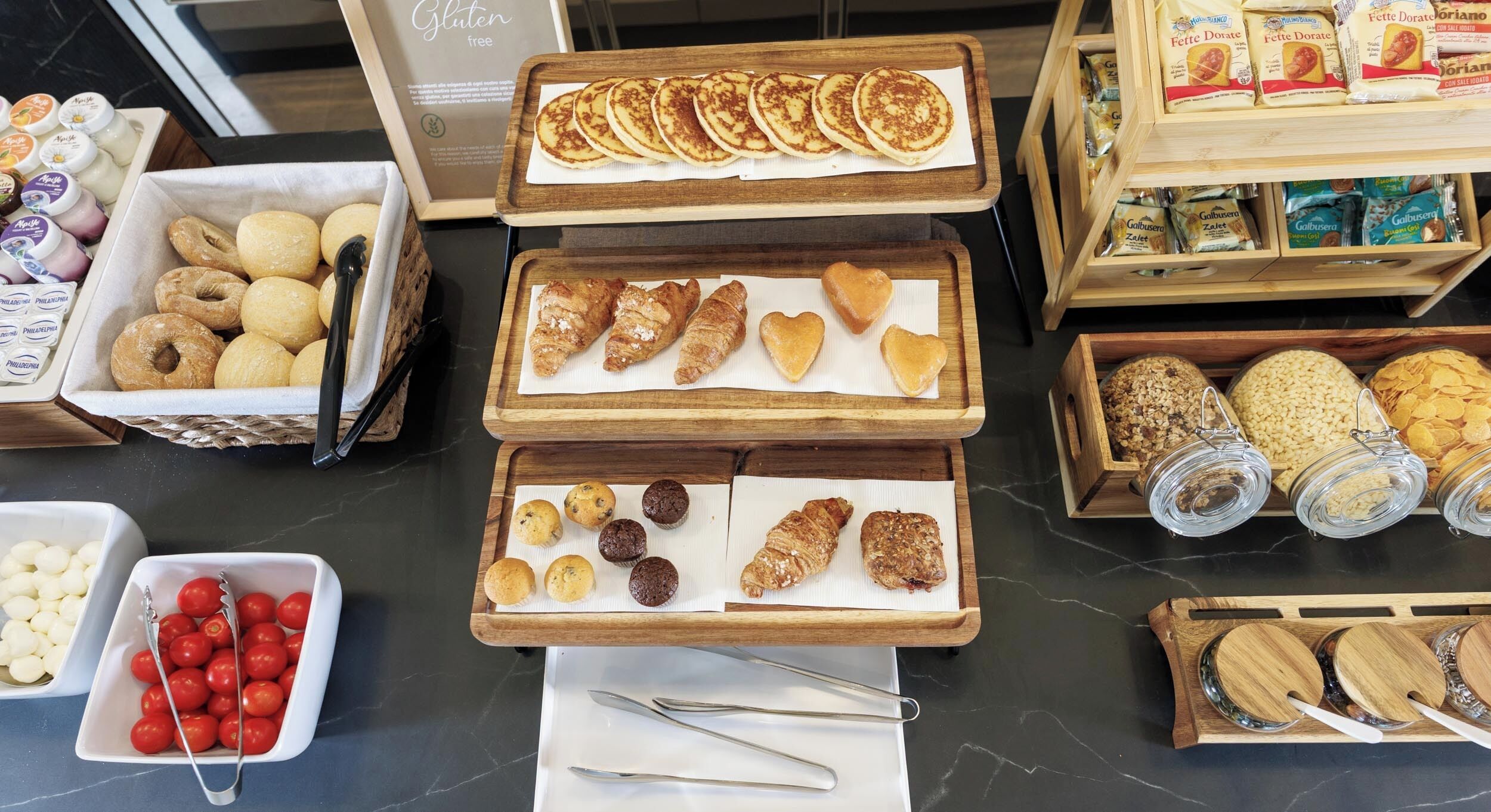 A variety of baked goods displayed on wooden trays, including pastries, muffins, and cookies.