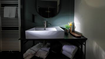 Un baño con lavamanos blanco, un espejo y un perchero para toallas.