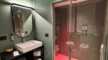 Un bagno moderno con uno specchio grande, un lavandino, un mobile bagno nero e un'area doccia vetrata.