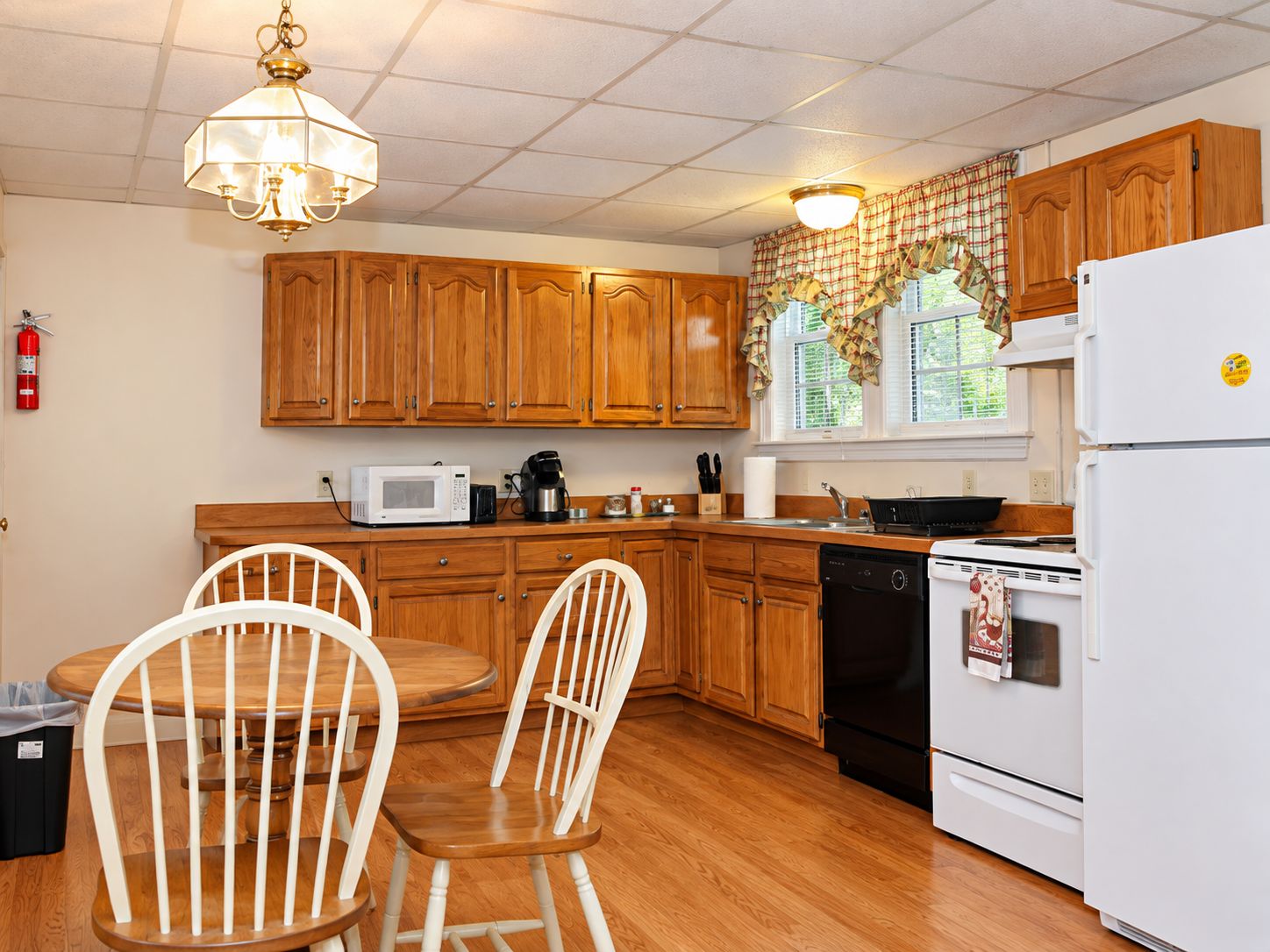 A kitchen with wooden cabinets, a white refrigerator, a microwave, a coffee maker, and a dishwasher.