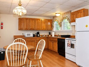 A kitchen with wooden cabinets, a white refrigerator, a microwave, a coffee maker, and a dishwasher. - Portland 1-bedroom with enclosed porch & parking (Portland)