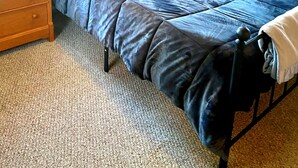 A bedroom with a bed, a nightstand, a dresser, and a window with curtains. - Portland 1-bedroom with enclosed porch & parking (Portland)