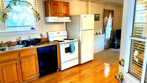 A compact kitchen with wooden cabinets, a white stove, and a refrigerator. - Portland 1-bedroom with enclosed porch & parking (Portland)