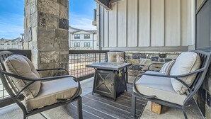 Un balcon orné de piliers en pierre, deux fauteuils confortables, une petite table et une vue sur les bâtiments voisins.