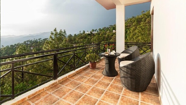 A balcony with a view of a mountainous landscape, a potted plant, and wicker furniture. - Maple Resort Chail (Chail)