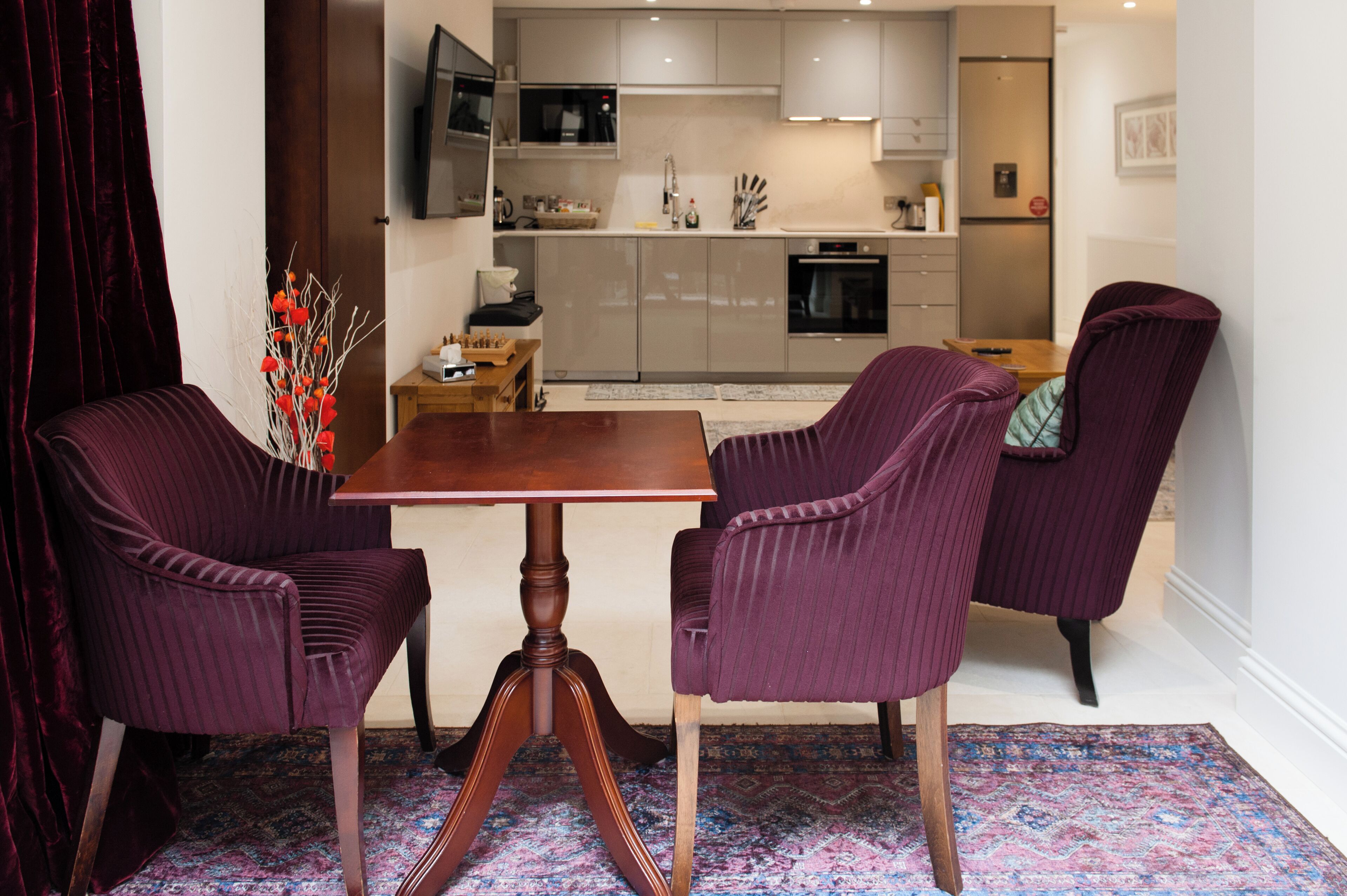 A modern kitchen with a dining area featuring a wooden table and purple upholstered chairs.