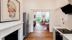A kitchen with a white countertop, a refrigerator, and a fireplace. - 21 Montpellier Terrace (Cheltenham)