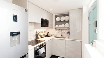 Een moderne keuken met witte kastjes, een ingebouwde oven, een waterdispenser en een spoelbak.