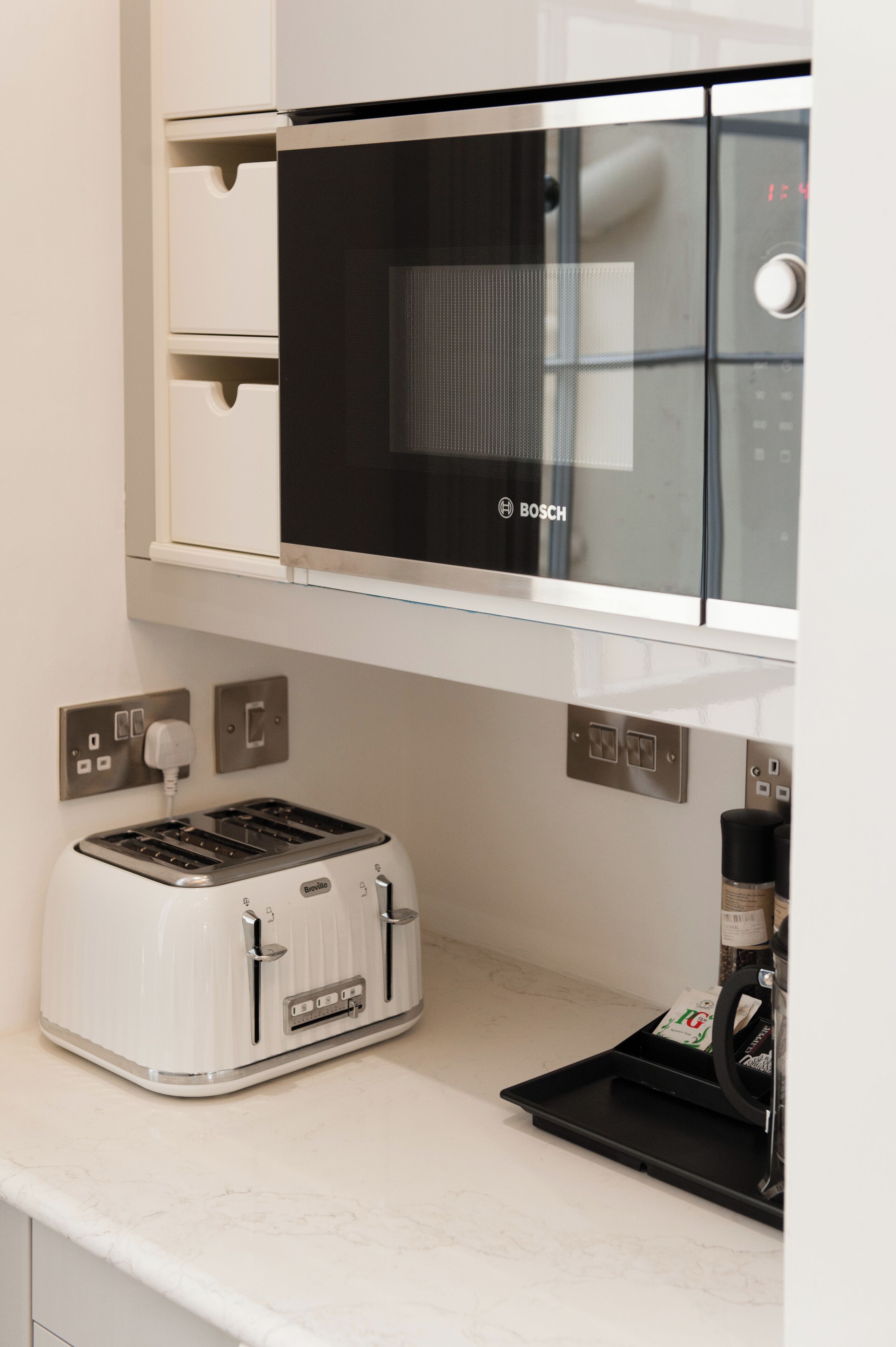 A kitchen with a Bosch microwave, a white toaster, and a coffee machine on the counter.