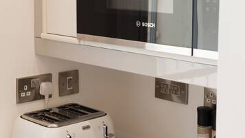 A kitchen with a Bosch microwave, a white toaster, and a coffee machine on the counter.