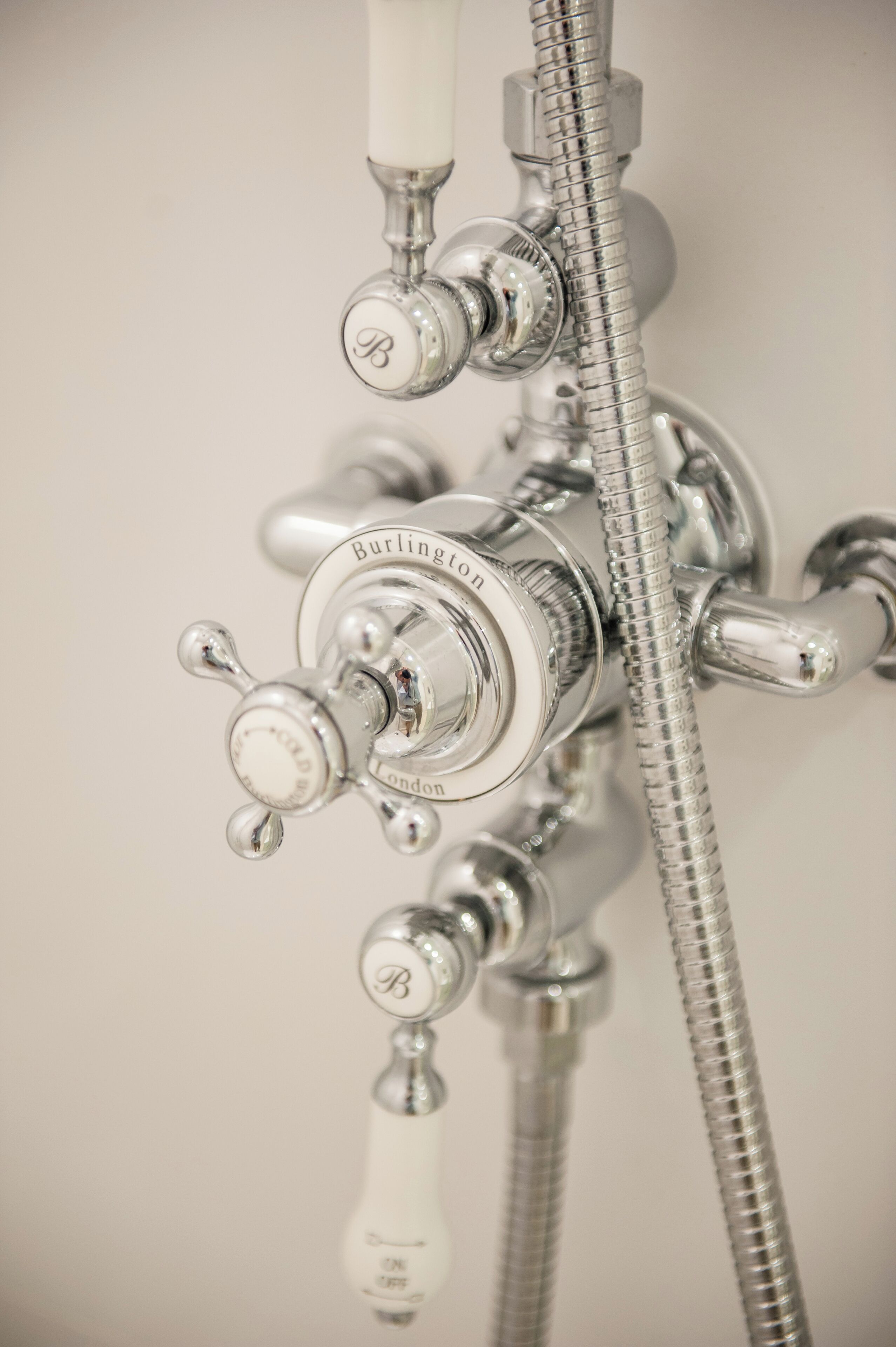 A bathroom with a chrome faucet and showerhead, labeled "Burlington London."