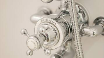 Une salle de bain avec un robinet et une pomme de douche en chrome, portant l’inscription « Burlington London ».