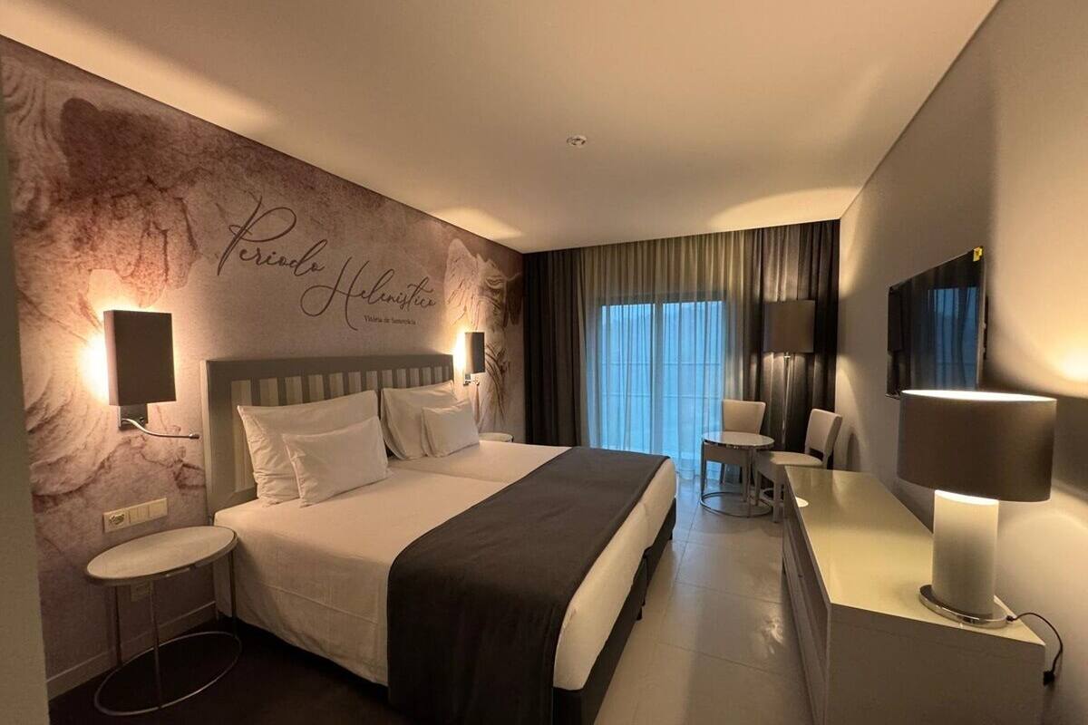Een moderne hotelkamer met een groot bed, nachtkastjes, een bureau en een televisie.