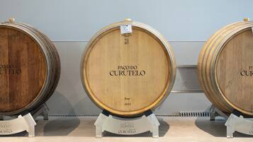 Three wooden barrels labeled 'Paco do Curutelo' with a metal stand in a storage area.