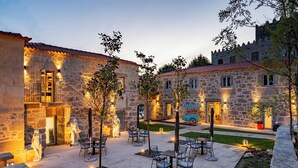 Un patio con edificios de piedra, asientos al aire libre y una estatua.