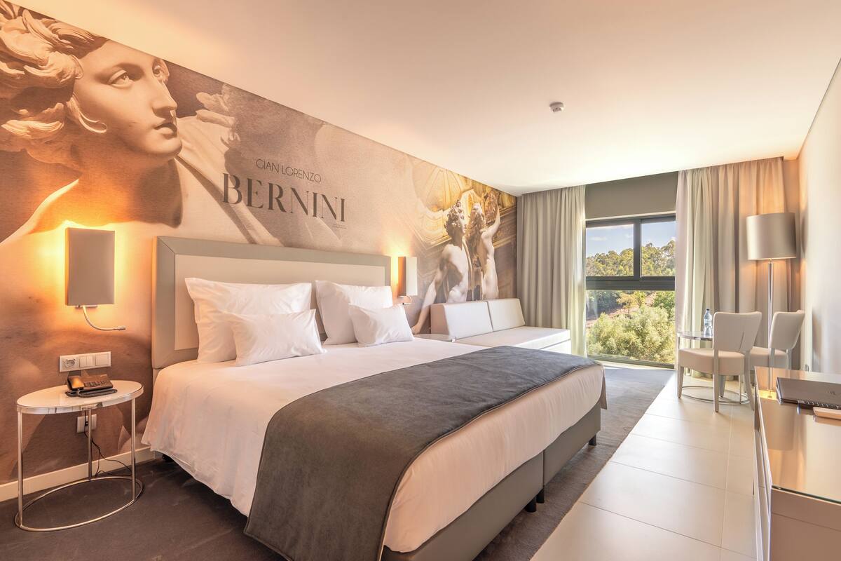 Een moderne hotelkamer met een groot bed, een bureau en uitzicht op de omgeving.