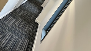 Un intérieur moderne avec un escalier recouvert de moquette, des murs blancs et une porte en bois.