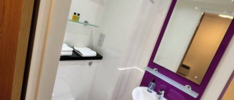 A compact bathroom with a white toilet, a pedestal sink, and a mirror above the sink.